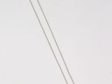a silver necklace with a cross on it sitting on a white surface