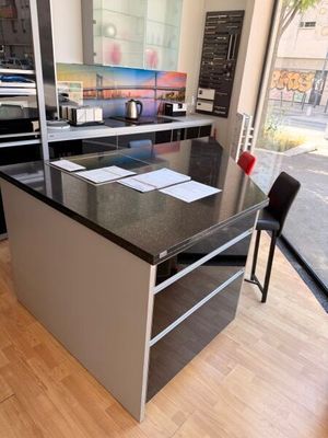 a kitchen with a black counter top and black chairs