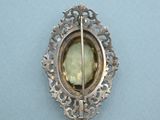 a silver brooch with a green stone in it
