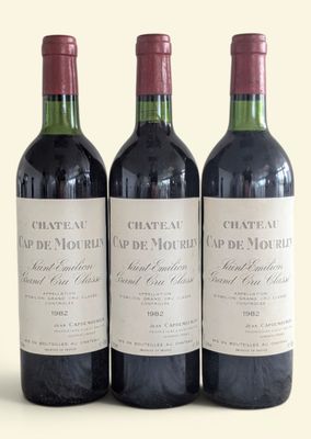 three bottles of red wine are lined up on a white surface