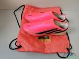 pink tennis shoes in a drawsack bag on a white surface