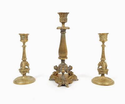 three antique brass candlesticks on a white background