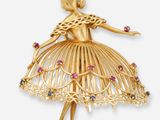 un gros plan sur une broche en or représentant une ballerine