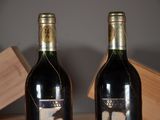 two bottles of wine sitting on a table with a box in the background