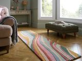 un salon avec un canapé, un fauteuil, un pouf et un tapis
