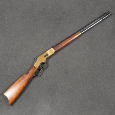 un fusil avec une crosse en bois posé sur une surface grise