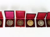six gold and silver coins in a red box on a white surface