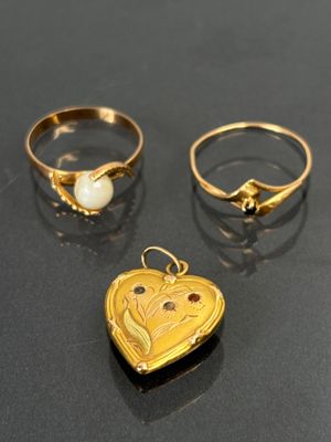deux bagues en or et un cadenas en forme de cœur posés sur une table