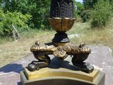 une lampe noire et dorée posée sur un socle au milieu d'un champ