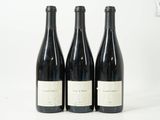 trois bouteilles de vin sont alignées sur une surface blanche