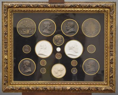 a framed picture of a group of coins with a picture of a man and a woman