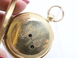 a person holding a gold pocket watch in their hand