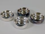 four metal bowls are lined up in a row on a white surface