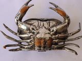 a silver crab that is sitting on a white surface