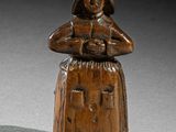 une vieille figurine en bois représentant une femme tenant un panier