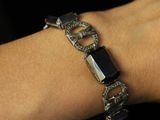 someone is wearing a bracelet with a black stone on it