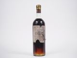 une vieille bouteille de whisky posée sur une surface blanche