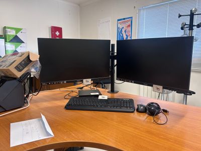 a desk with two monitors and a keyboard on it