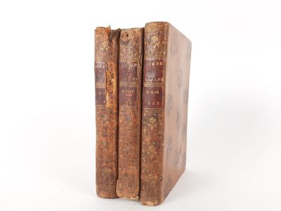 two old books sitting on top of each other on a white surface