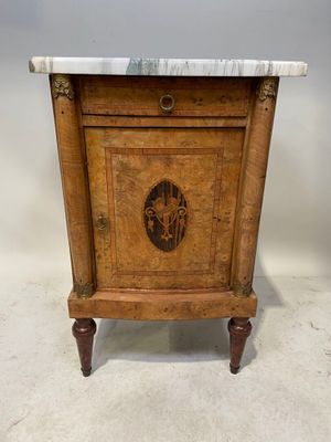 une vieille armoire en bois avec un plateau en marbre, posée sur un socle
