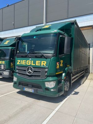three green trucks parked in front of a building