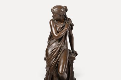 une statue en bronze représentant une femme tenant un panier