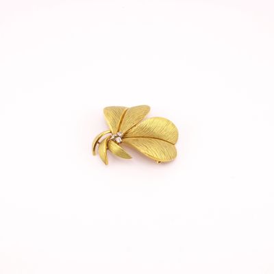 un gros plan d'une broche en feuille d'or sur fond blanc