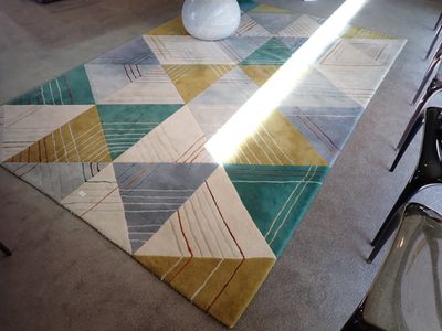 une table sur laquelle se trouve un vase et un tapis posé au sol
