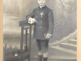 an old photo of a man in uniform standing next to a chair