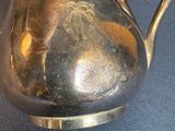a person holding a silver tea pot on a table