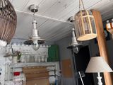 a table with a lamp and a birdcage hanging from it ' s ceiling