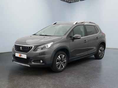 La voiture grise est garée dans une grande pièce au sol noir.