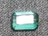un gros plan d'une émeraude verte sur une surface grise