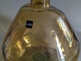 a yellow glass vase with a black label on it