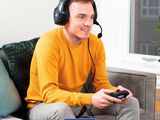 a man sitting on a couch wearing headphones and holding a video game controller