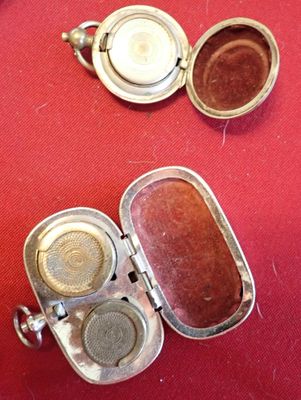 two small silver containers with lids on a red table