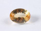 a close up of a yellow sapphire stone on a white surface
