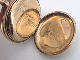 a gold pocket watch with a chain on a white surface