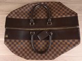 brown and black checkered duffel bag on a wooden floor
