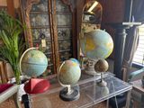 three globes sitting on a clear table in a living room