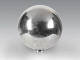 une boule argentée brillante posée sur un socle, sur une surface blanche