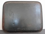 an old metal tray with a handle sitting on a table