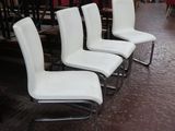Plusieurs chaises blanches sont alignées dans une pièce, avec un lustre en arrière-plan.