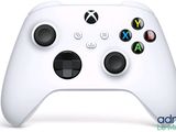 un gros plan d'une manette Xbox blanche posée sur une surface blanche