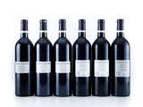 six bottles of wine are lined up in a row on a white surface