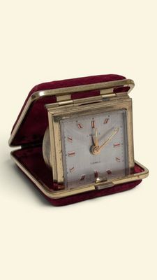 a small clock that is sitting in a red case