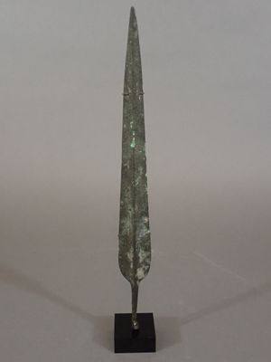 an image of a small bronze sword on a black stand