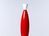 un vase rouge avec un couvercle blanc posé sur une table