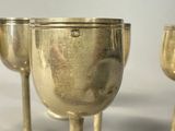 three silver goblets sitting on a white table