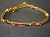 un gros plan sur un bracelet en or orné de pierres roses